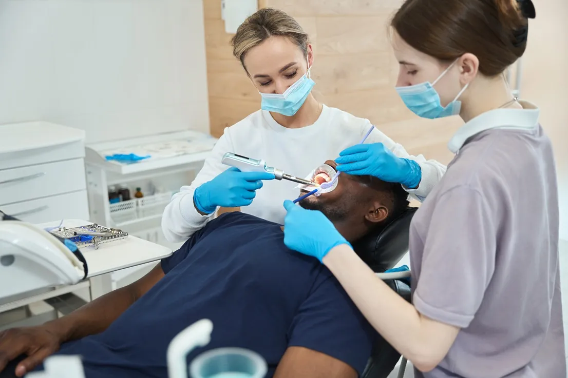 Odontoiatra e assistente durante una visita, con il paziente sulla poltrona